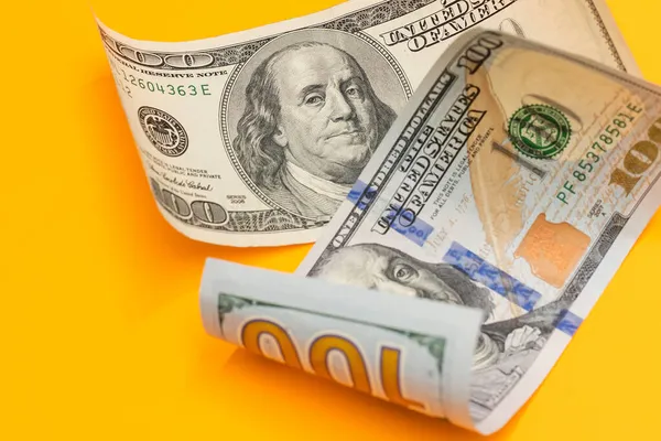 Cem dólares Bill Enrolado em amarelo — Fotografia de Stock