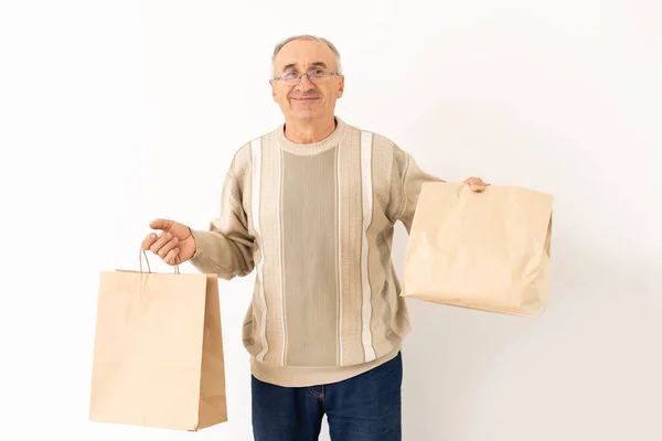 Portrait of pensioner elderly retired cheerful grey-haired man buying goods isolated over bright background — Stock Photo, Image