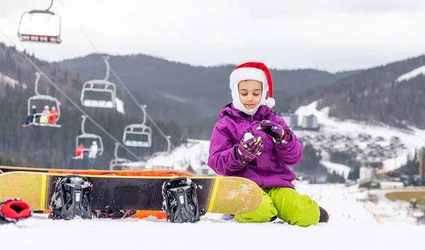 Menina feliz em santa chapéu com snowboard — Fotografia de Stock