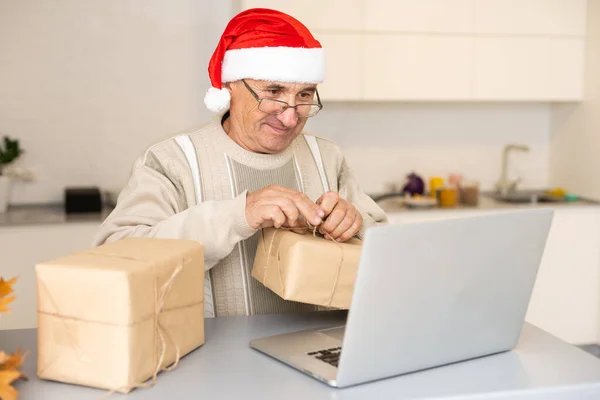 Літній джентльмен святкує Різдво онлайн в ноутбуці робить відеодзвінок з віддаленою сім'єю сидить на кухні вдома. Новорічне свято — стокове фото