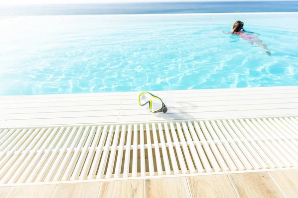 Maschera da nuoto con boccaglio vicino alla piscina blu in una soleggiata mattina tropicale — Foto Stock