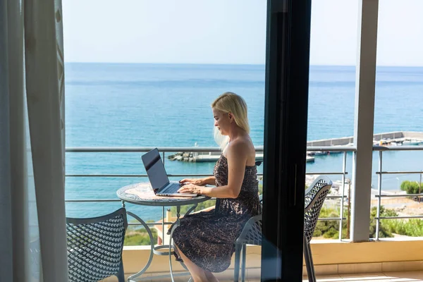 Femme dans la chambre d'hôtel avec ordinateur portable et vue sur l'océan — Photo