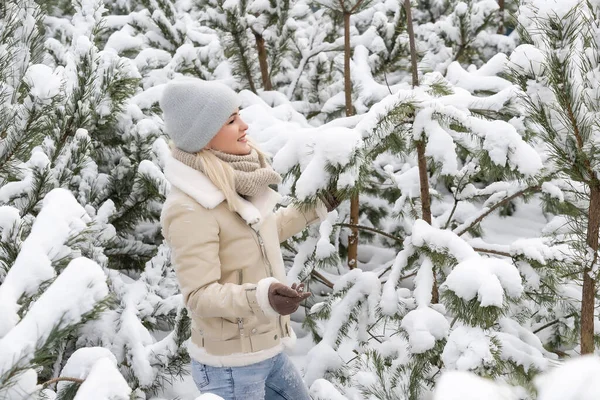 Ein Mädchen in weißen Kleidern steht neben einer Kiefer im Schnee. — Stockfoto