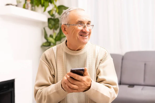 Tecnologia, persone, stile di vita e concetto di comunicazione felice uomo anziano comporre il numero di telefono e sms su smartphone a casa. — Foto Stock