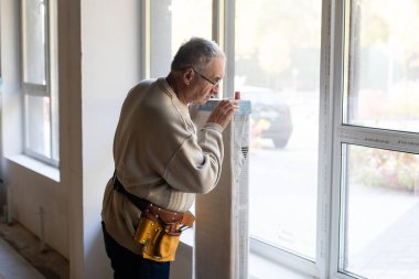 İş yerindeki tesisatçı. Su ısıtma radyatörü kuruluyor