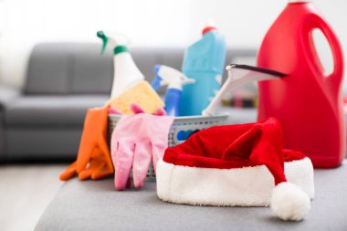 Noel temizliği. Noel alışverişi. Noel Baba şapkası arka planındaki temizleme araçları ve Noel süslemeleri