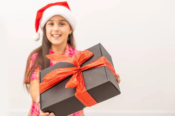 Sorrindo criança engraçada no chapéu vermelho de Santa. Segurando presente de Natal na mão. Conceito de Natal. sobre fundo branco — Fotografia de Stock