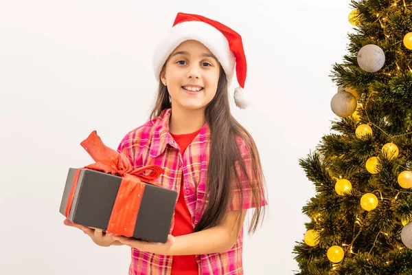 Посміхається смішна дитина в червоному капелюсі Санта. Тримаючи подарунок на Різдво в руці. Різдвяна концепція. на білому тлі — стокове фото