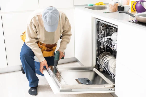 Nézet az ember általános javítása mosogatógép a konyhában — Stock Fotó