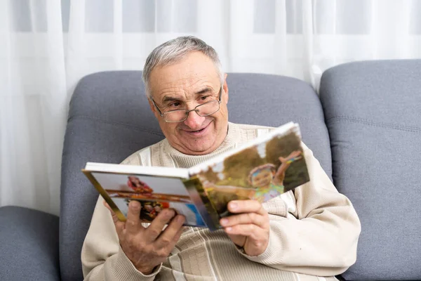An old man in a hospital ward watching photobook — Stock Photo, Image