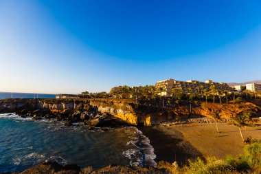 Tropik Tenerife adası. Atlantik Okyanusu 'ndaki bir İspanyol şehrinin kıyısında. Tenerife adasındaki şehir ve sahil manzarası. Gradyan ve tahıllı arkaplan rengi, ses efekti