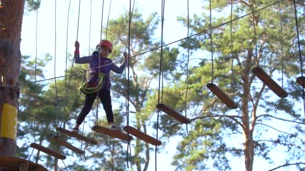 어린 소녀가 로프 위에서 서 손으로 밧줄을 잡고 있습니다. 밧줄 공원에 있는 어린이는 장애물을 지나간다 — 비디오
