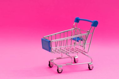 Pembe arka planda izole edilmiş bir alışveriş arabası.