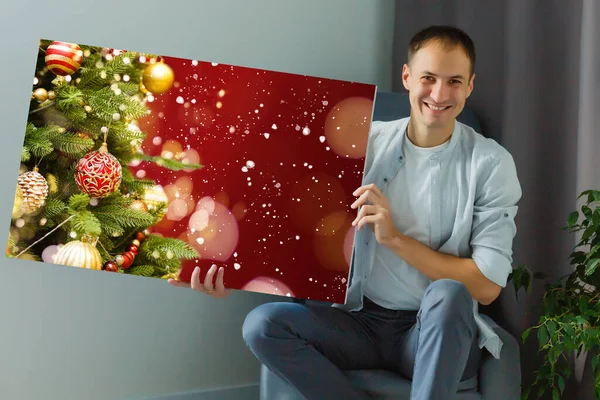 Un uomo in possesso di una tela fotografica con una foto di Natale — Foto Stock