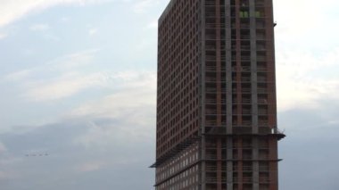 Bir grup uçak çok katlı apartmanların üstündeki bulutlu gökyüzünde uçuyor. Profesyonel askeri pilotlar geçit töreni ya da hava gösterisi için hazırlanıyor. askeri tatbikatlar.