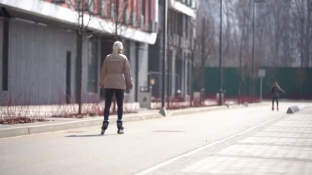 Moeder onderwijzen dochter roller skating in de stad Park in slow motion. Achteraanzicht. Familie sport activiteiten buitenshuis. Mensen, kinderen, jeugd concept. — Stockvideo