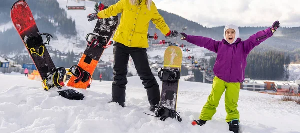 Mãe e filha com snowboards estão brincando na neve — Fotografia de Stock