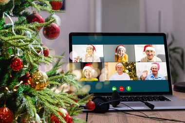 Sanal Noel partisi. Video konferansında genç bir adamın ev ofisteki bilgisayarla görüntülü konuşma yapması Online takım hediye konferansı..