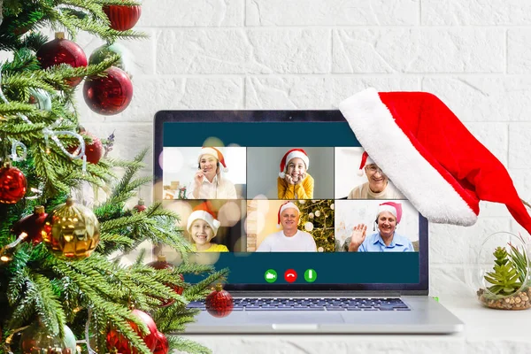 Voeux de Noël en ligne. une femme en pull blanc et chapeau rouge Santa utilise un ordinateur portable pour faire des appels vidéo à des amis, parents, et pour les achats en ligne — Photo