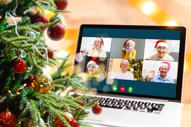 Noel selamları çevrimiçi. Beyaz kazaklı ve kırmızı şapkalı bir kadın arkadaşlarına, ailelerine ve online alışveriş için bilgisayar kullanıyor.