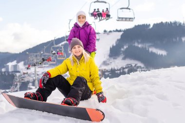 Anne ve kızı kış tatilinde snowboard yapıyor.