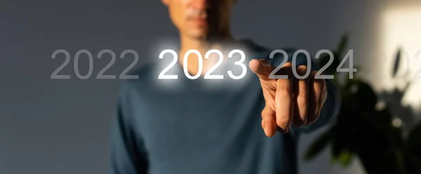 Stisknutím modrého tlačítka Start 2023 na virtuálním rozhraní na šedém pozadí s kopírovacím prostorem pro text. Koncept nového roku. Podnikatel zmáčkl 2023 a začal podnikat. Začátek nového roku 2023 — Stock fotografie