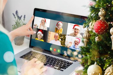 Sanal Noel partisi. Video konferansında genç bir adamın ev ofisteki bilgisayarla görüntülü konuşma yapması Online takım hediye konferansı..