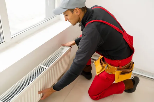 Workman montage radiateur de chauffage de l'eau près de la fenêtre dans le salon rénové blanc, Image avec espace de copie — Photo