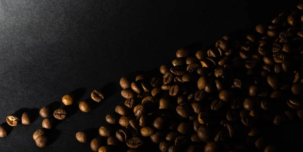 Högen kaffebönor isolerad på svart bakgrund och konsistens, ovanifrån. — Stockfoto