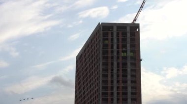 Bir grup uçak çok katlı apartmanların üstündeki bulutlu gökyüzünde uçuyor. Profesyonel askeri pilotlar geçit töreni ya da hava gösterisi için hazırlanıyor. askeri tatbikatlar.
