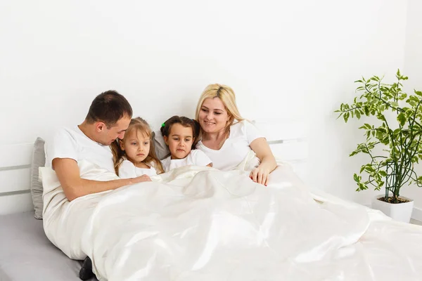 Νεαρή οικογένεια αναπαύεται μαζί στο κρεβάτι των γονιών — Φωτογραφία Αρχείου