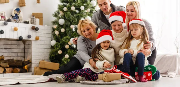 Glückliche junge Familie hält Weihnachtsgeschenk und lächelt — Stockfoto