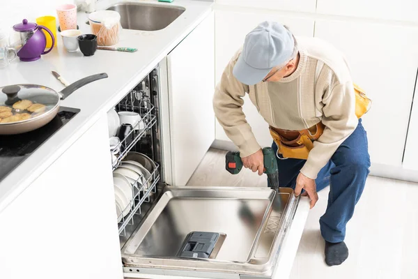 Nézet az ember általános javítása mosogatógép a konyhában — Stock Fotó