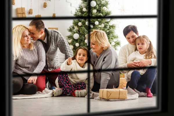 Gran familia con tres niños celebrando la Navidad en casa. Cena festiva en la chimenea y árbol de Navidad. Padres e hijos comiendo en la chimenea en la habitación decorada. Iluminación infantil vela de la corona de adviento . — Foto de Stock
