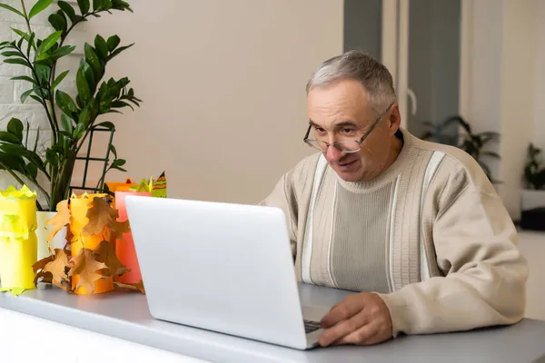 Uomo anziano con computer portatile e video da nipoti — Foto Stock