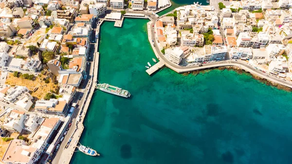 Agios Nikolaos. Kréta. Řecko. Budovy na břehu jezera Voulismeni a čluny u mola — Stock fotografie