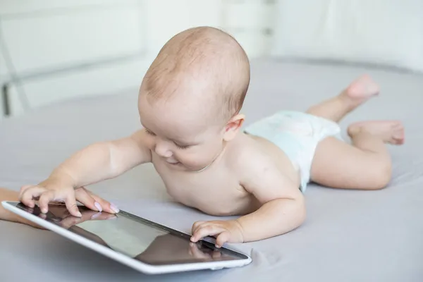 Een baby van zes maanden met een tablet computer, naar het scherm kijkend, thuis — Stockfoto