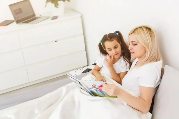 Madre e figlia a letto guardando un album fotografico — Foto Stock