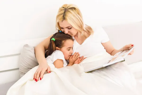 Мати і дочка в ліжку дивиться фото книги — стокове фото