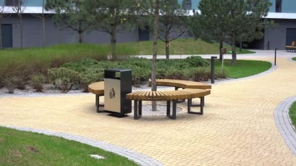 Um banco moderno com um canteiro de flores em um parque da cidade em um dia ensolarado. Melhoria da cidade, planejamento urbano, espaços públicos. — Vídeo de Stock