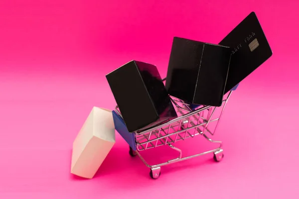 Bevásárlókosár és ajándékdobozok rózsaszín háttérrel — Stock Fotó