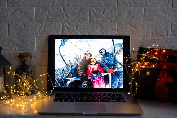 クリスマスツリーの背景の前に木製のテーブルの上にオープンノートパソコンの家族やクリスマスのイメージ — ストック写真