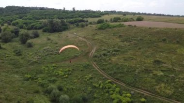 Tepe manzarasında paraşütü olan bir adam.