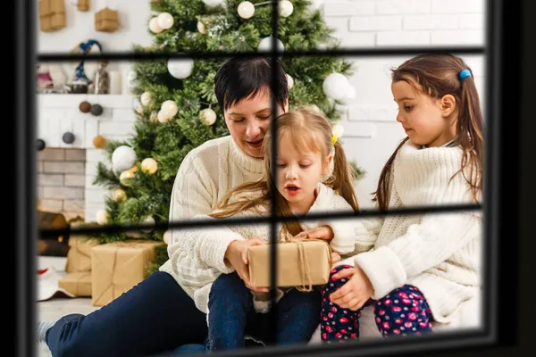Gran familia con tres niños celebrando la Navidad en casa. Cena festiva en la chimenea y árbol de Navidad. Padres e hijos comiendo en la chimenea en la habitación decorada. Iluminación infantil vela de la corona de adviento . — Foto de Stock