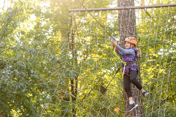 Meisje klimmen in adventure park is een plaats die kan bevatten een grote verscheidenheid van elementen, zoals touwklimmen oefeningen, hindernisbanen en zip-lijnen. — Stockfoto