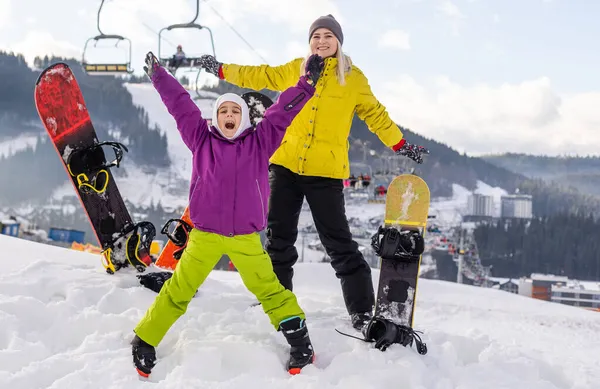 Mãe e filha com snowboards no resort de inverno — Fotografia de Stock
