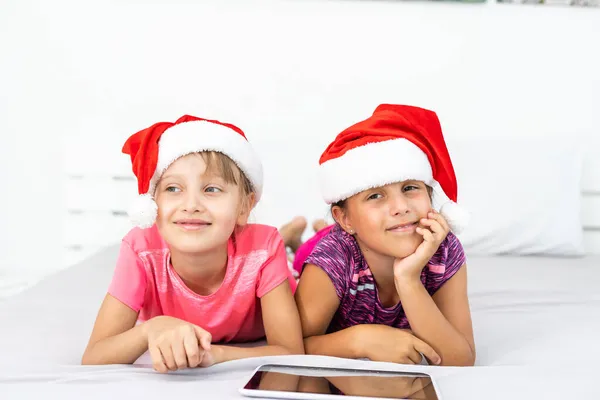 Yeni yıl konsepti. Noel, Noel, Noel, kış, mutluluk konsepti. Tabletle oynayan iki sevimli kız. — Stok fotoğraf