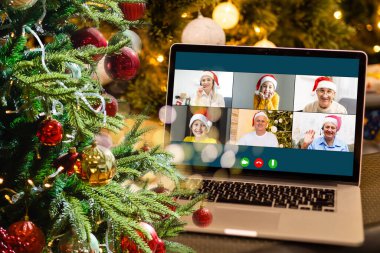 Sanal Noel partisi. Video konferansında genç bir adamın ev ofisteki bilgisayarla görüntülü konuşma yapması Online takım hediye konferansı..