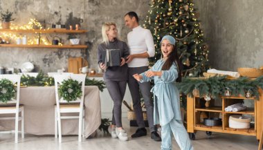 Noel Ailesi. Mutluluk. Baba, anne ve kızın Noel ağacının yanındaki portresi, hepsi gülümsüyor.