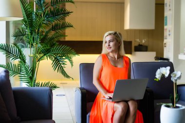 Otel lobi çalışma dizüstü bilgisayar, kanepede oturan genç kadın